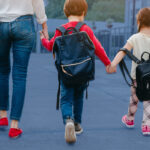 mom with kids walking with backpacks on