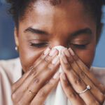 woman blowing her nose into a tissue