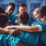 nurses gathering in a circle with arms around themselves