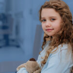 young girl sitting with a stuffed animal