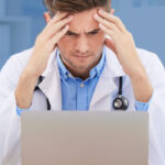 doctor frustrated in front of a laptop